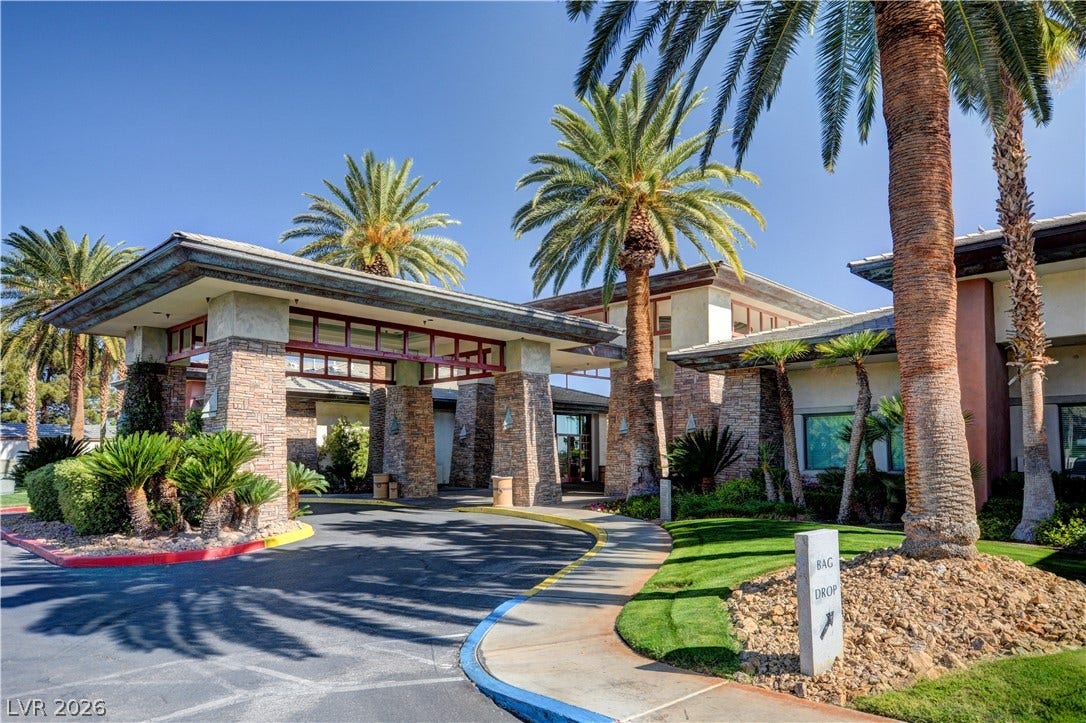115 Cora Hills Court, Las Vegas, NV 89148 A grand circular driveway leads to a resort-style porte-cochre, flanked by mature palm trees and lush landscaping.