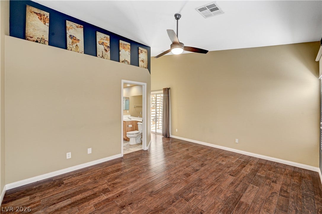 115 Cora Hills Court, Las Vegas, NV 89148 A spacious primary bedroom features rich wood flooring, vaulted ceilings, and a convenient ensuite bathroom.