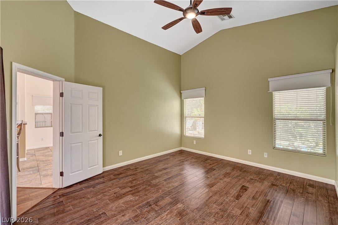 115 Cora Hills Court, Las Vegas, NV 89148 A well-lit bedroom features vaulted ceilings, ample windows, and richly toned wood flooring.