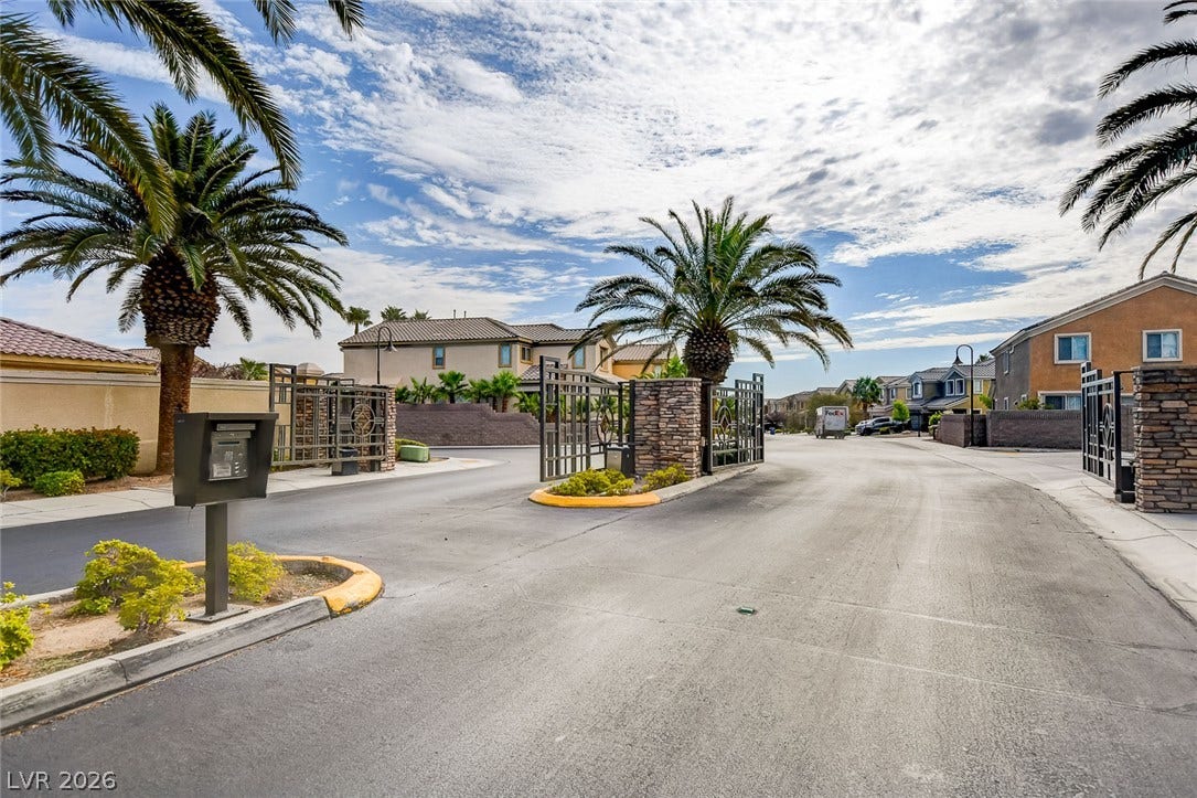 115 Cora Hills Court, Las Vegas, NV 89148 Ornate wrought iron gates welcome residents into this exclusive community, framed by lush palm trees and inviting architecture.