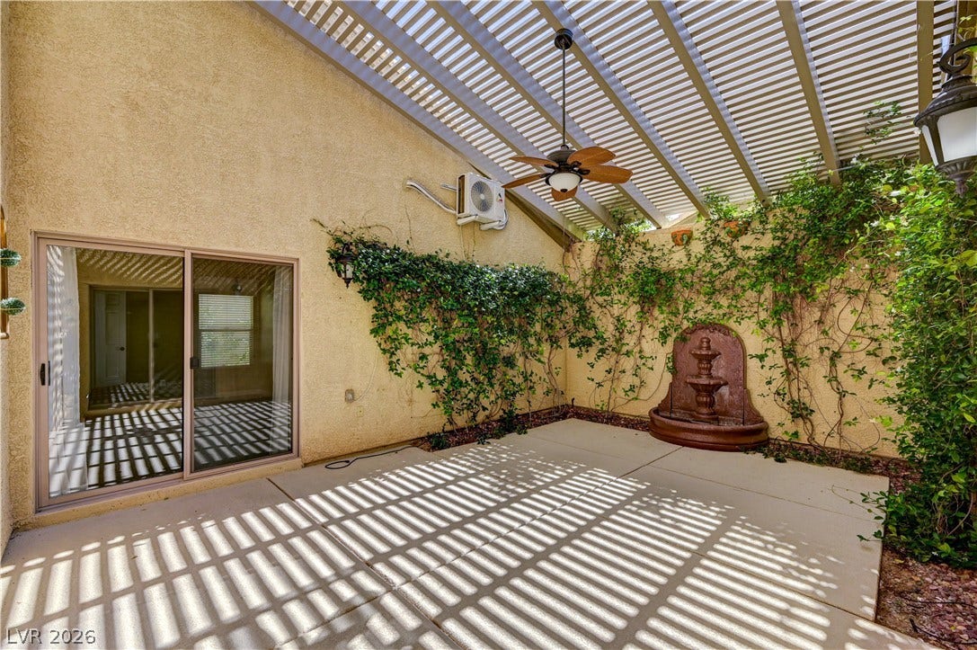 115 Cora Hills Court, Las Vegas, NV 89148 A tranquil outdoor living space, featuring a serene fountain and shaded by a slatted pergola, awaits relaxation.