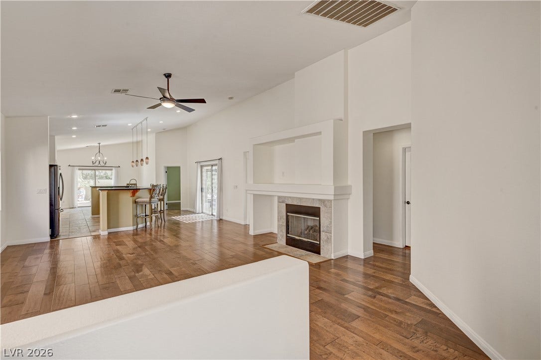 115 Cora Hills Court, Las Vegas, NV 89148 Vast open-concept living space with vaulted ceilings, a cozy fireplace, and abundant natural light.