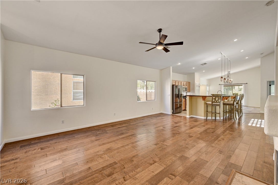 115 Cora Hills Court, Las Vegas, NV 89148 Natural light illuminates this spacious living area, featuring rich wood flooring and a modern ceiling fan.