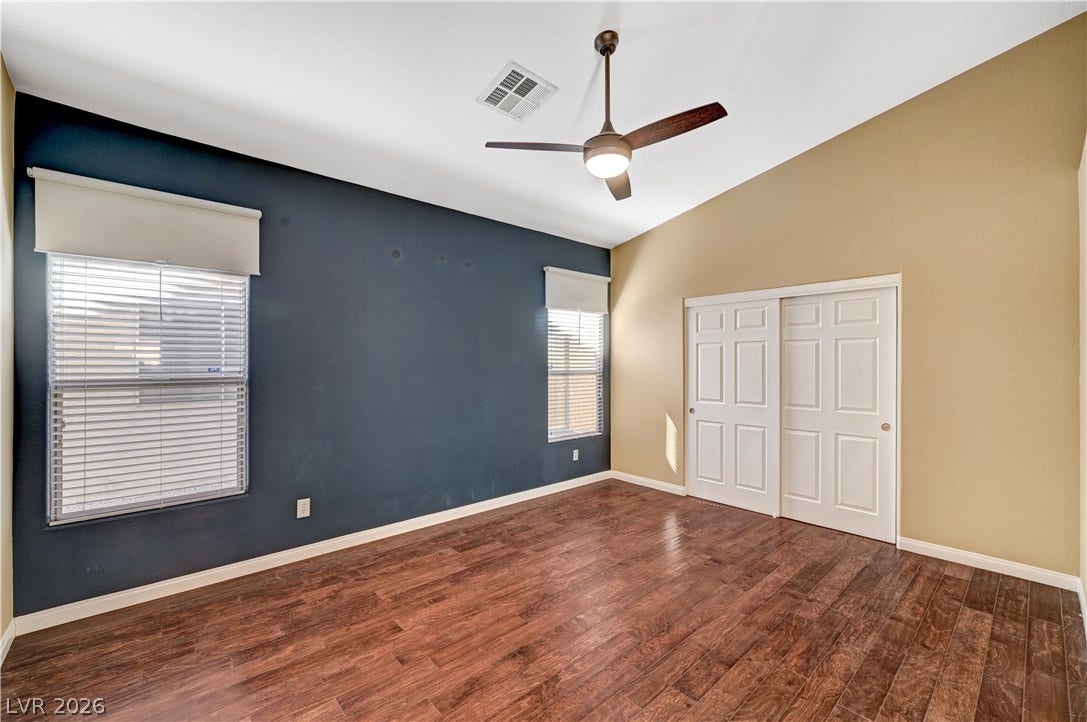 115 Cora Hills Court, Las Vegas, NV 89148 Rich hardwood-style flooring extends across this spacious bedroom, complemented by a ceiling fan for optimal comfort.