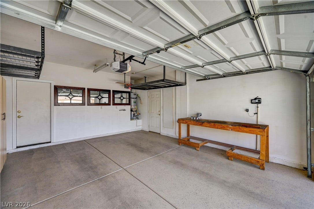 115 Cora Hills Court, Las Vegas, NV 89148 A spacious, clean garage featuring practical overhead storage and a sturdy workbench.