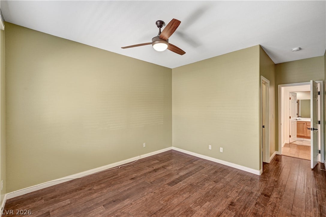 115 Cora Hills Court, Las Vegas, NV 89148 Rich hardwood-style flooring and a modern ceiling fan define this versatile bedroom space.