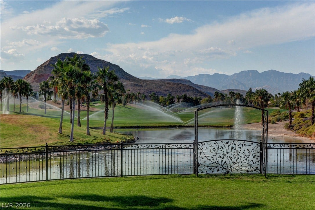 115 Cora Hills Court, Las Vegas, NV 89148 A tranquil golf course vista unfolds, featuring mature palm trees and a reflective water hazard with a decorative fence.