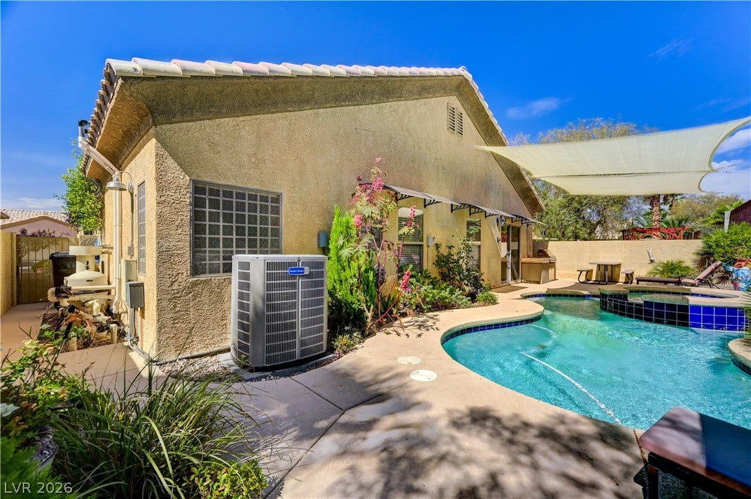115 Cora Hills Court, Las Vegas, NV 89148 A tranquil backyard oasis features a freeform pool and inviting spa, perfect for outdoor enjoyment.