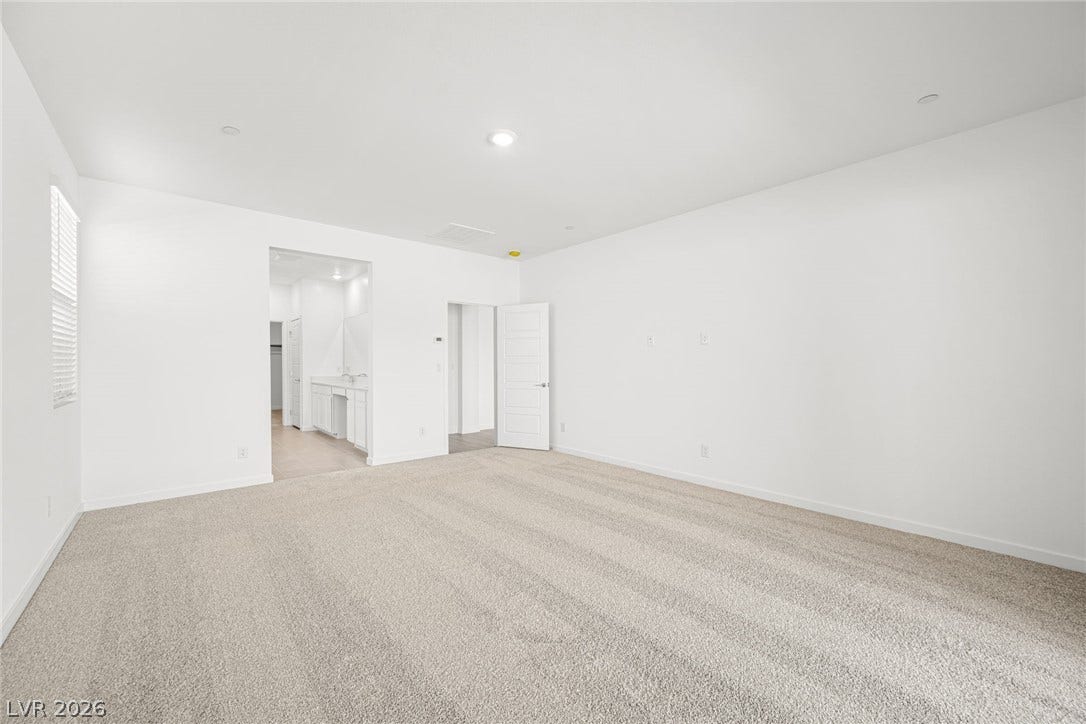 Well-lit and spacious, this primary bedroom features plush carpet and seamless access to an ensuite.