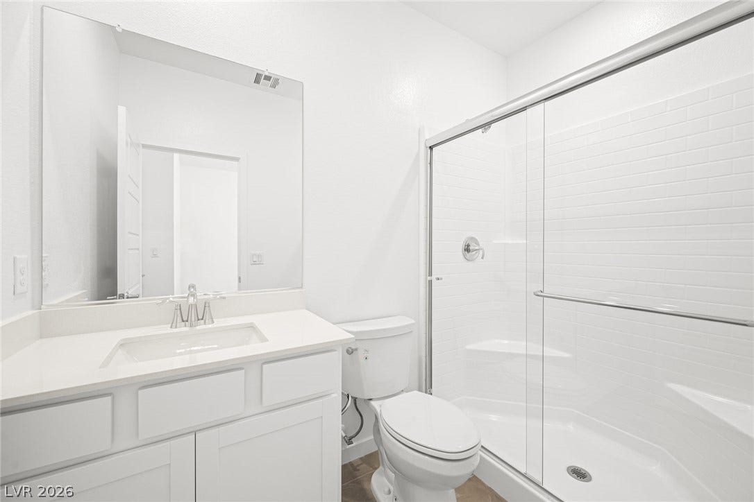A well-appointed bathroom features a modern vanity and a spacious, glass-enclosed shower.