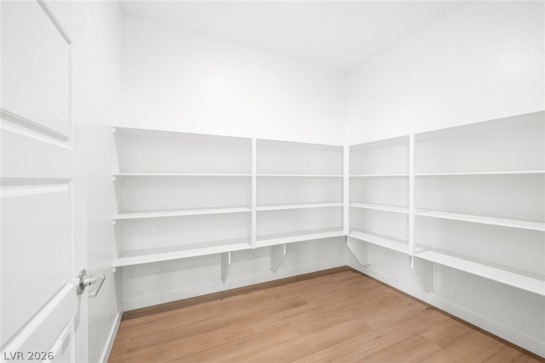 Ample built-in shelving and warm wood-look flooring define this organized pantry.
