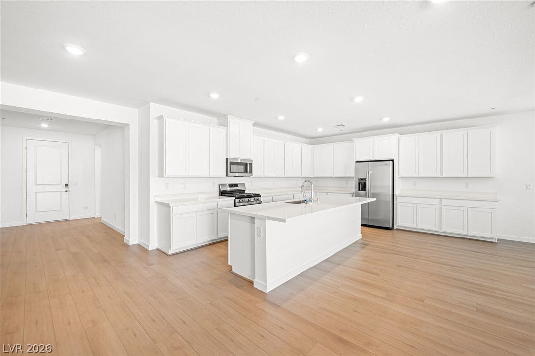 Culinary delights await in this bright kitchen with a spacious island, pristine countertops, and light wood flooring.