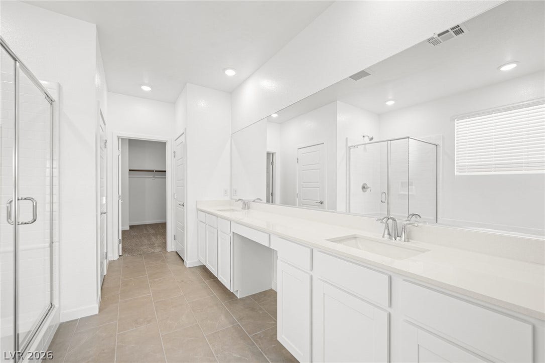 A generously sized primary bath features a dual vanity, separate shower, and a large walk-in closet beyond.