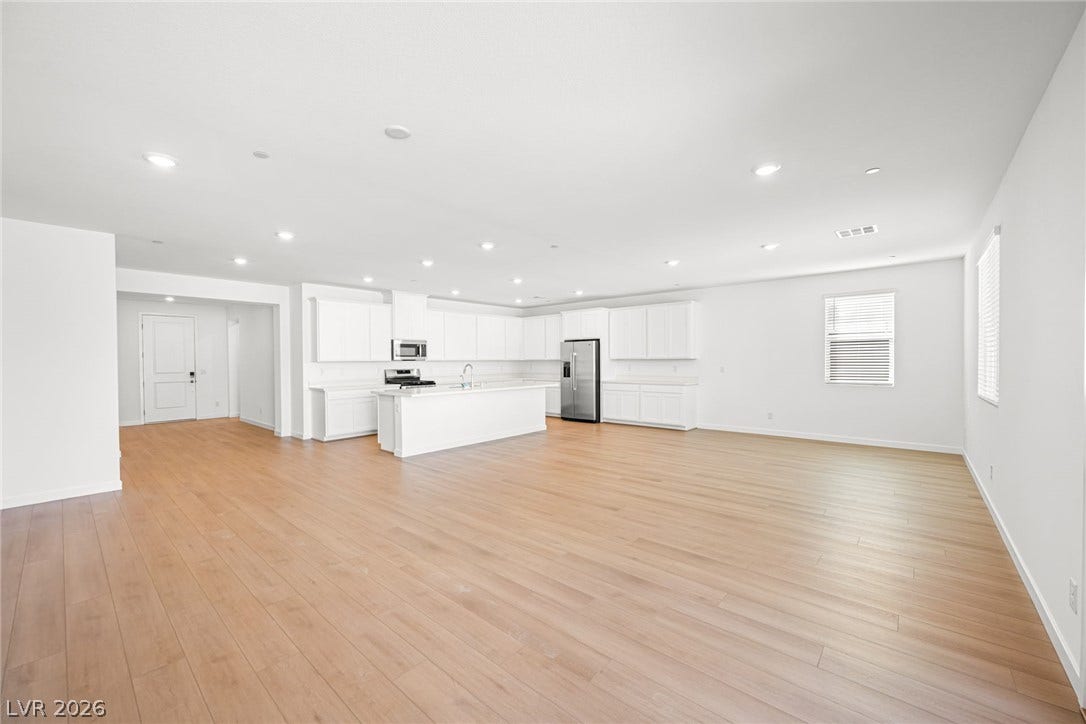 A spacious, naturally illuminated kitchen and living area with continuous hardwood flooring throughout.