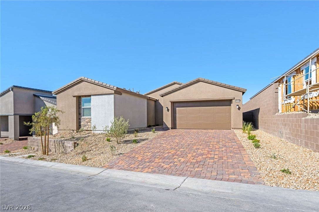 A neatly paved brick driveway leads to this modern desert dwelling with a tidy, low-maintenance landscape.