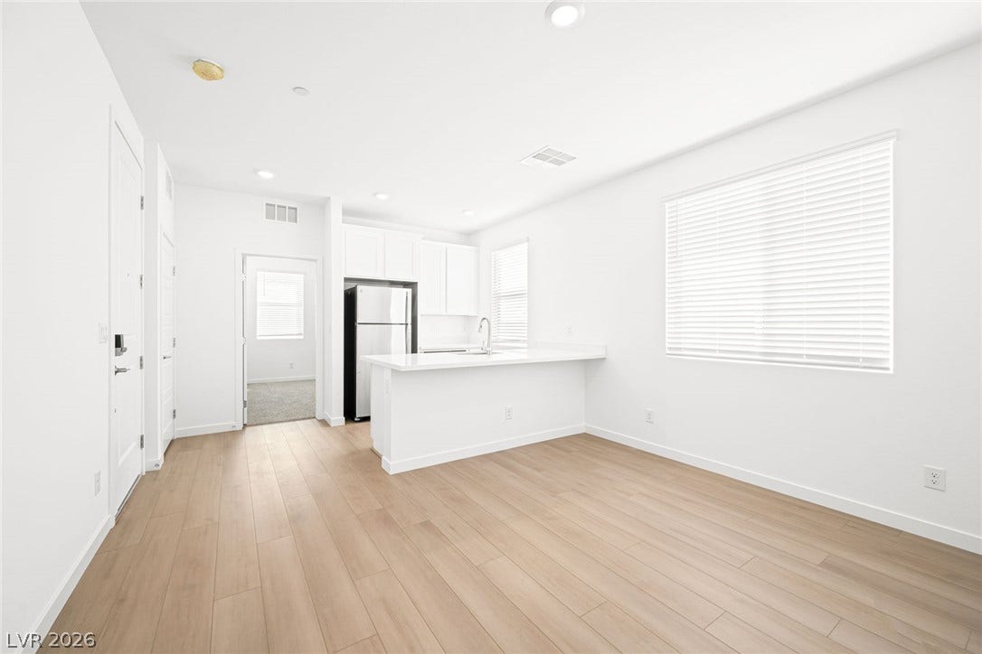 The open-concept layout connects a contemporary kitchen with light wood flooring throughout the space.