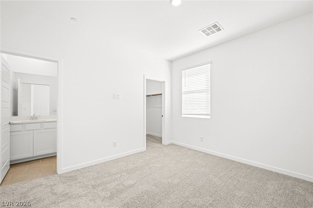 A spacious room features plush carpet and an adjacent full bathroom.