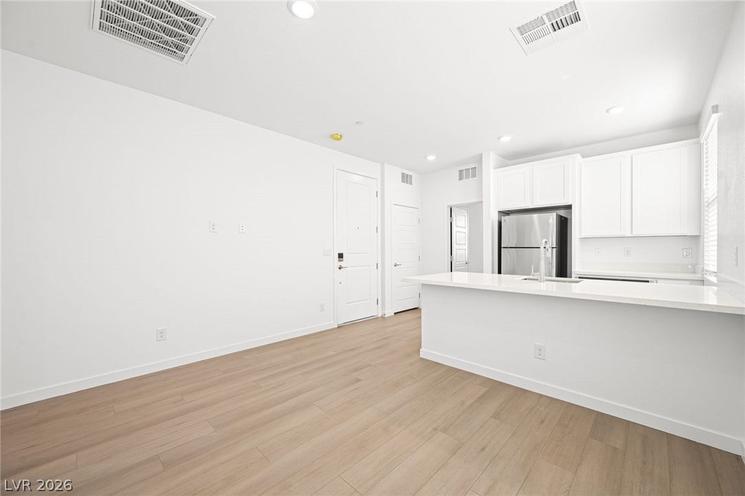 A well-lit, open-concept living space with resilient flooring transitions seamlessly into a sleek, modern kitchen.
