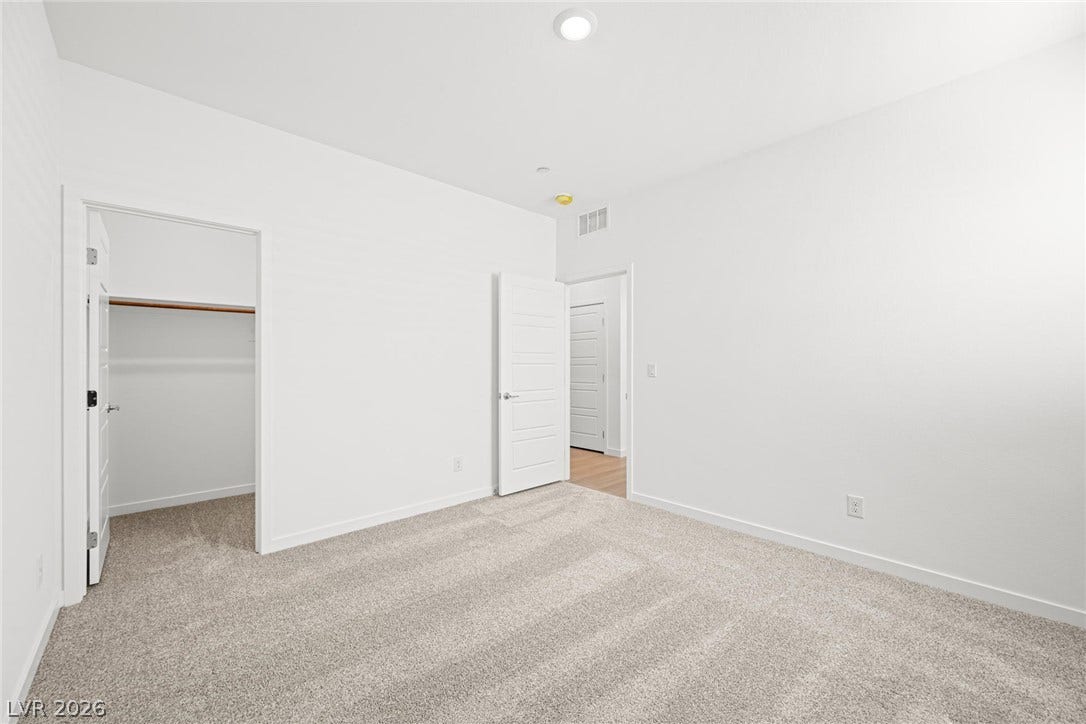 A spacious chamber with pristine white walls, recessed lighting, and soft carpeting awaiting your personal touch.