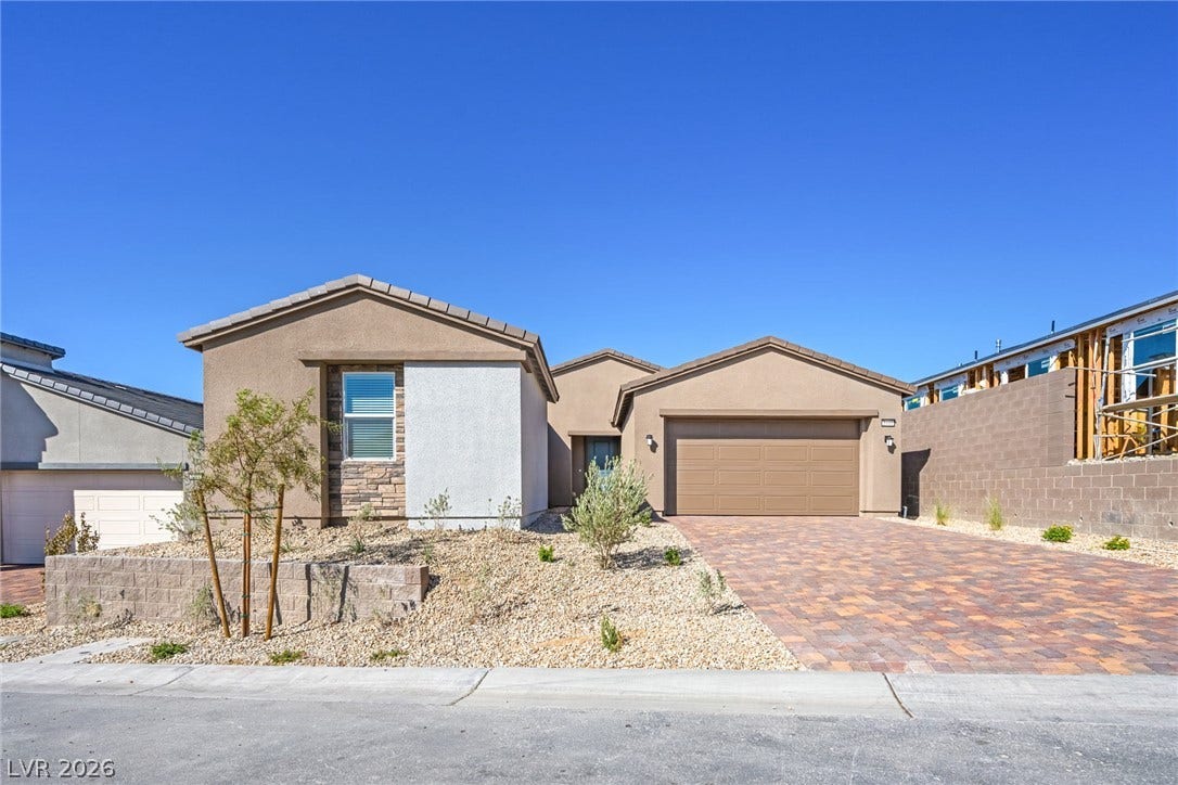 A desert-friendly landscape surrounds this inviting home, featuring a stylish paver driveway and attached garage.