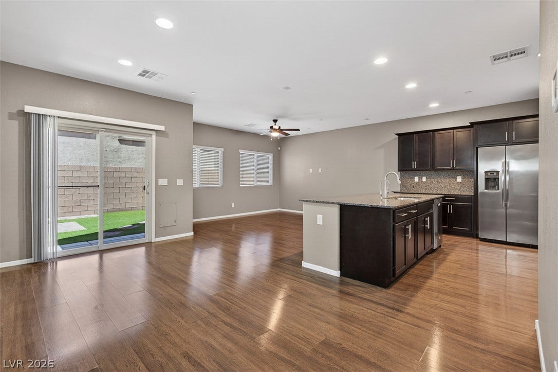 1146 Jesse Harbor Avenue, Henderson, NV 89014 A gleaming wood floor extends throughout this open-concept kitchen and living area, featuring a central island and sliding glass doors to the outside.