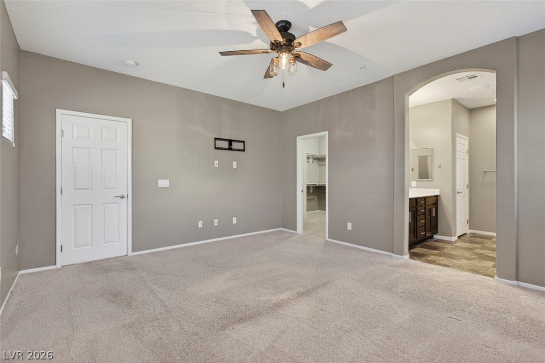 1146 Jesse Harbor Avenue, Henderson, NV 89014 A spacious primary bedroom features soft carpeting, a modern ceiling fan, and convenient access to an en-suite bathroom.