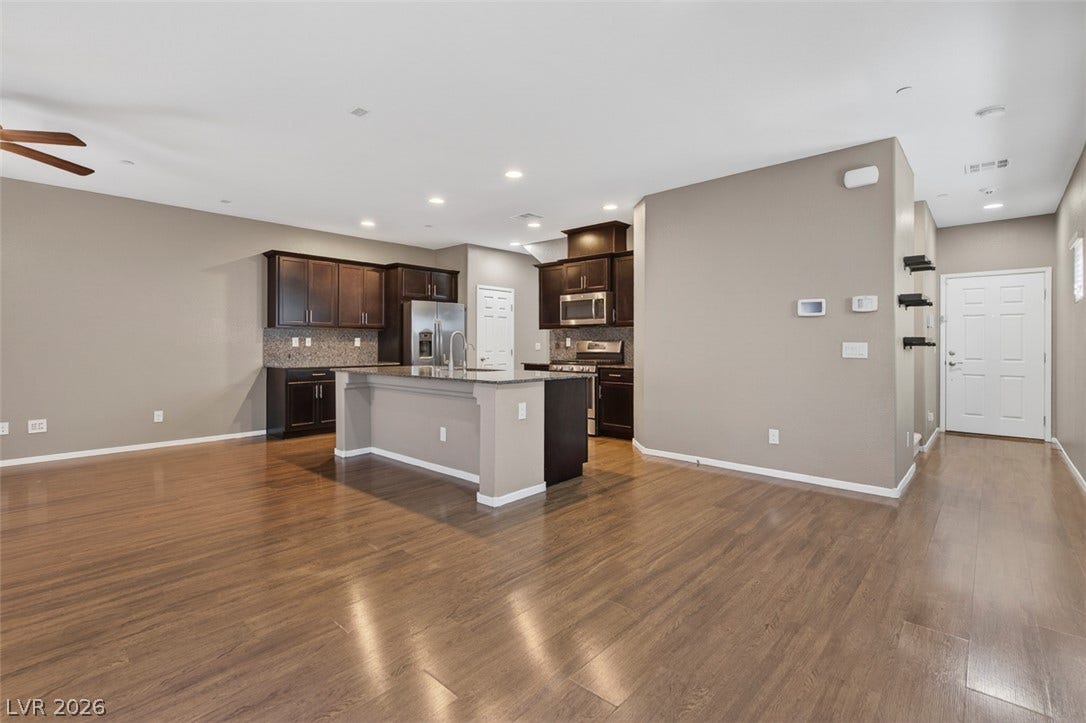 1146 Jesse Harbor Avenue, Henderson, NV 89014 An open-concept living area with lustrous hardwood flooring flows seamlessly into a modern kitchen, ideal for entertaining.