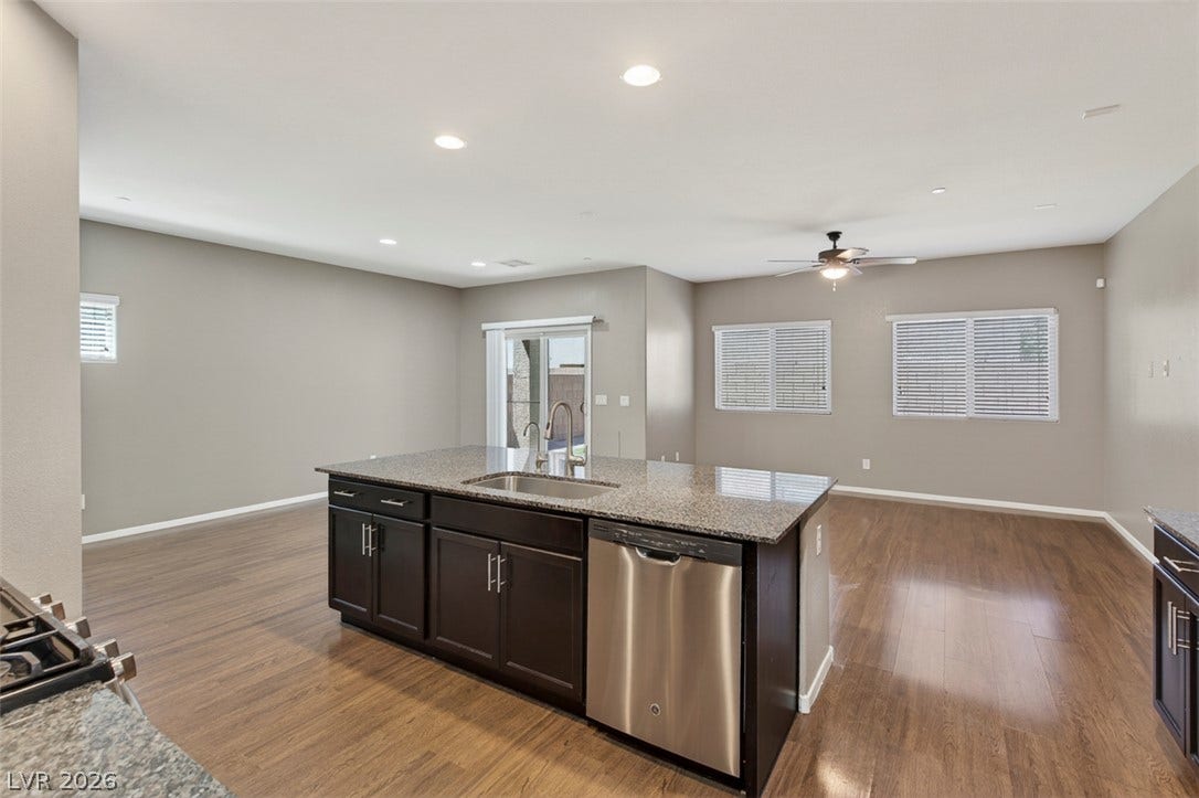1146 Jesse Harbor Avenue, Henderson, NV 89014 A well-lit kitchen featuring a granite island, ample cabinetry, and rich hardwood flooring, ready for culinary endeavors.