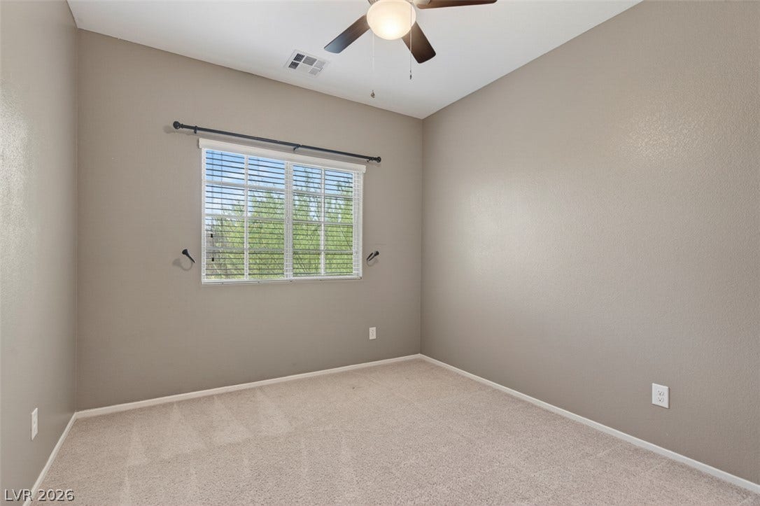 1146 Jesse Harbor Avenue, Henderson, NV 89014 A well-lit bedroom features plush carpeting, a large window, and a ceiling fan for comfort.