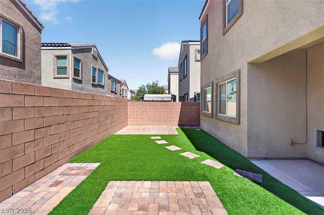1146 Jesse Harbor Avenue, Henderson, NV 89014 A low-maintenance yard features synthetic turf with paver stone accents, perfect for outdoor relaxation.