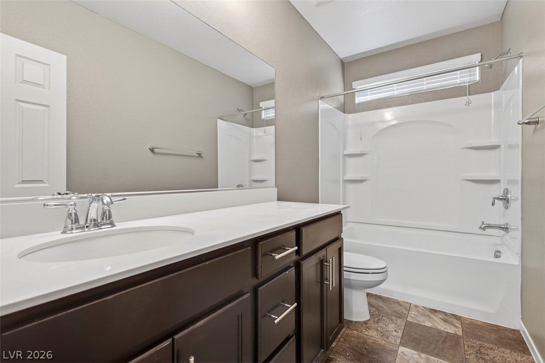 1146 Jesse Harbor Avenue, Henderson, NV 89014 A well-appointed bathroom offers a clean vanity with a large mirror and a pristine shower-tub combination.