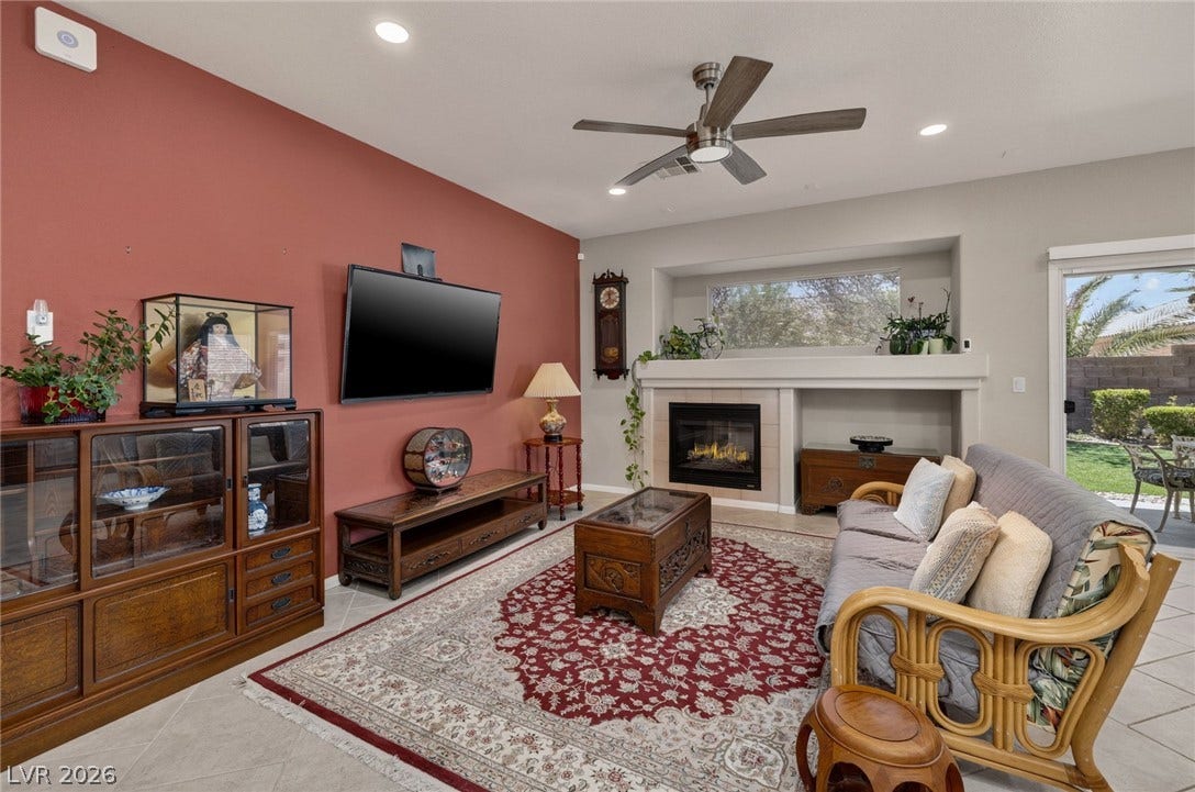 4467 Verdiccio Avenue, Las Vegas, NV 89141 A cozy living space features a modern fireplace and a wide, bright window with backyard views.
