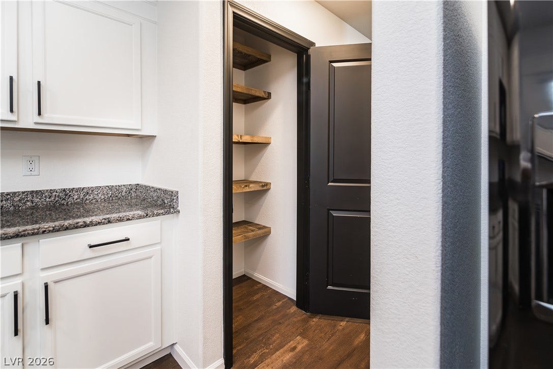 989 Harbor Avenue, Henderson, NV 89002 A well-appointed kitchen features white cabinetry and a convenient pantry with rustic wood shelving.