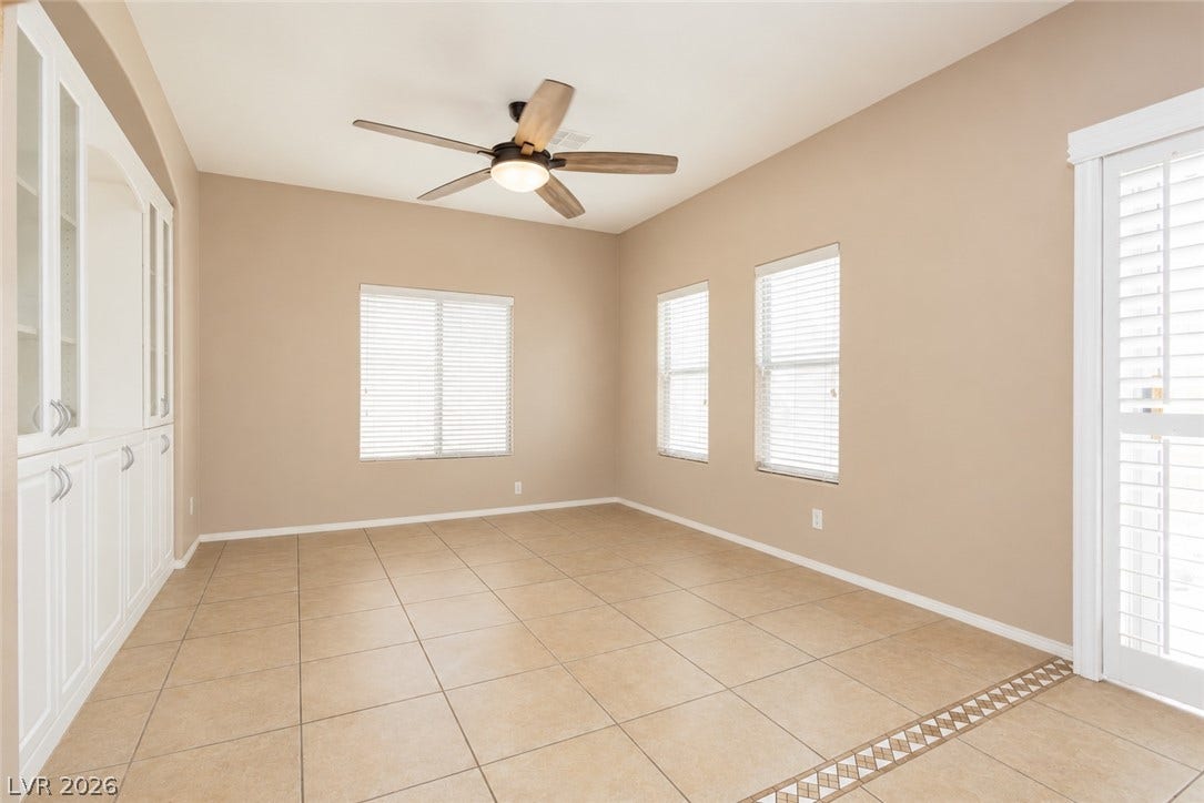 1176 Via Piazza, Henderson, NV 89052 Well-lit living area features tiled flooring and an entire wall of built-in storage with display cabinets.