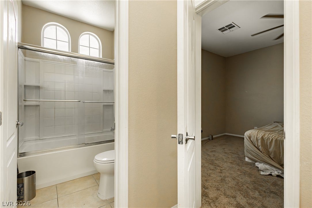 1176 Via Piazza, Henderson, NV 89052 Two arched windows adorn the top of a shower-tub combo, bringing light into this functional bathroom.