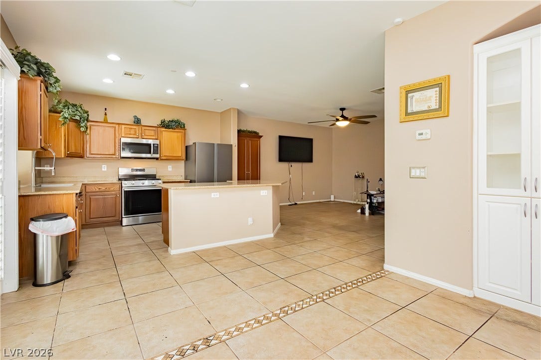 1176 Via Piazza, Henderson, NV 89052 A well-appointed kitchen with an island, granite counters, and stainless steel appliances flows seamlessly into the living space.