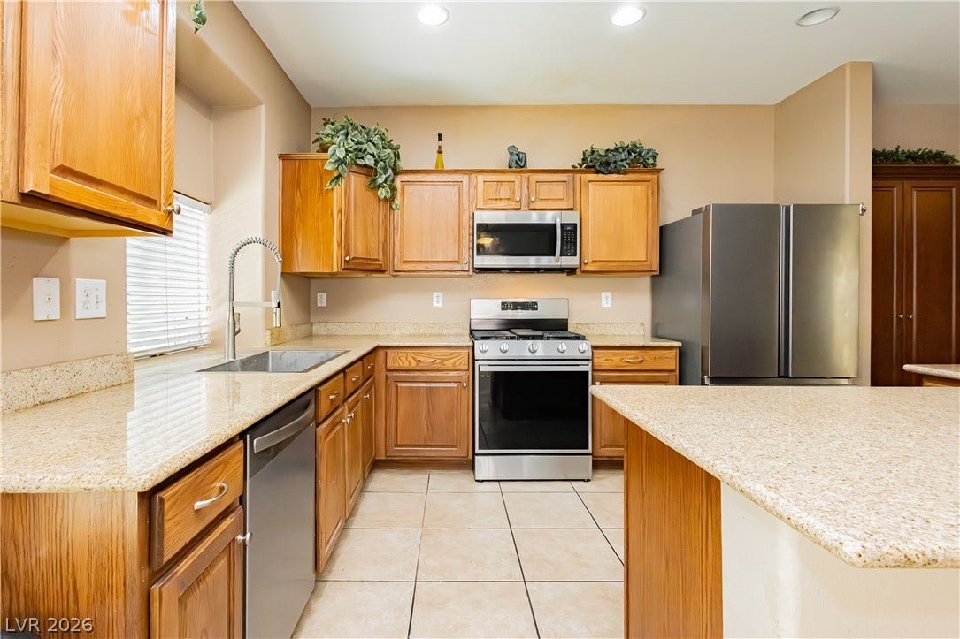 1176 Via Piazza, Henderson, NV 89052 A well-appointed kitchen features warm cabinetry, speckled countertops, and stainless steel appliances.