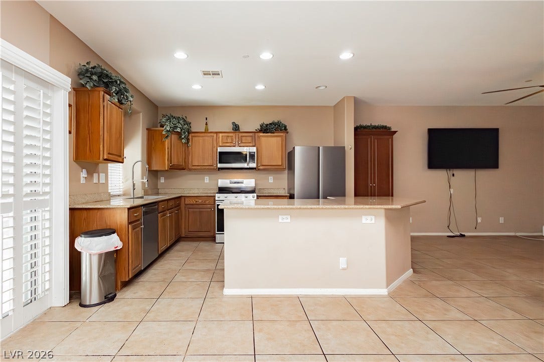 1176 Via Piazza, Henderson, NV 89052 Well-lit kitchen with a spacious island, granite countertops, and modern appliances.