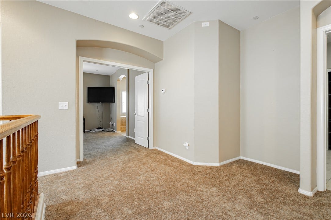 1176 Via Piazza, Henderson, NV 89052 A versatile secondary living space features plush carpeting and arched entryways.