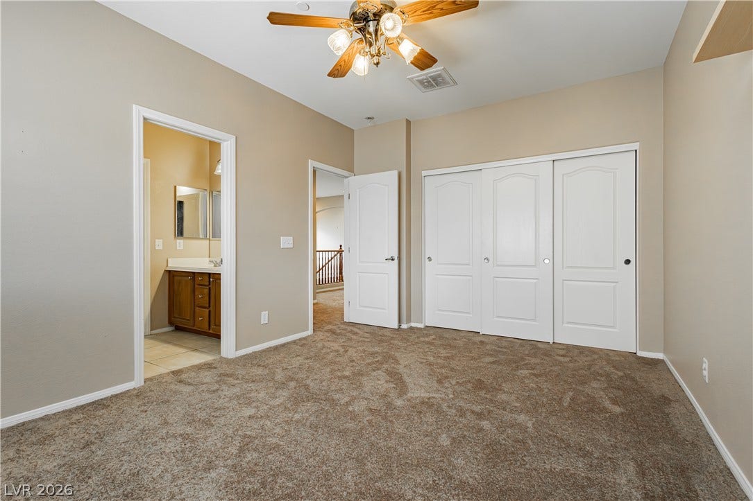 1176 Via Piazza, Henderson, NV 89052 A comfortable bedroom features plush carpeting, a ceiling fan, and convenient access to a private bathroom.