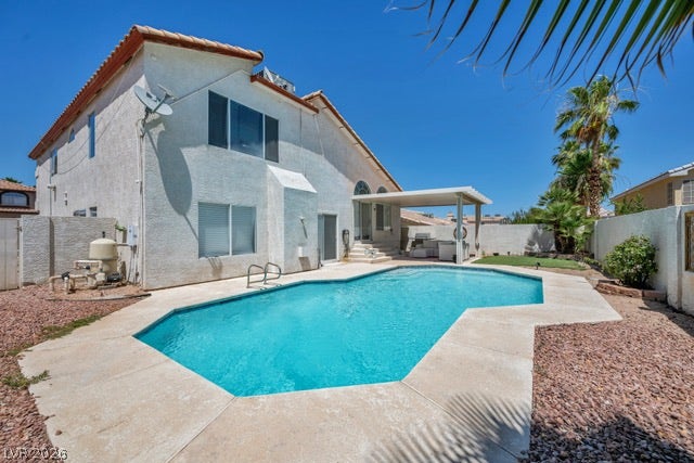2553 Hummingbird Hill Avenue, Henderson, NV 89074 A private backyard oasis features a glistening pool and shaded patio, perfect for enjoying sunny days.