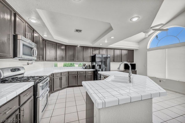2553 Hummingbird Hill Avenue, Henderson, NV 89074 Well-appointed kitchen offers plentiful cabinetry and an island with a sink, all beneath vaulted ceilings and a large arch window.