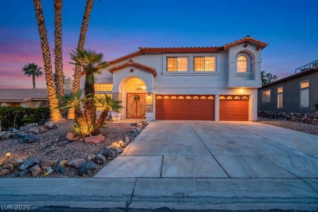 2553 Hummingbird Hill Avenue, Henderson, NV 89074 An inviting entry archway and vibrant palm trees create striking curb appeal at twilight.