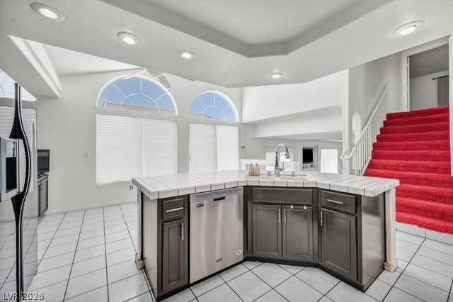 2553 Hummingbird Hill Avenue, Henderson, NV 89074 Bright white tiled kitchen with a U-shaped island, modern appliances, and arch-topped windows.