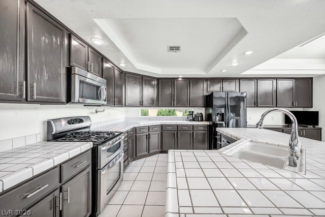 2553 Hummingbird Hill Avenue, Henderson, NV 89074 A functional kitchen provides ample dark cabinetry, tile countertops, and recessed lighting.