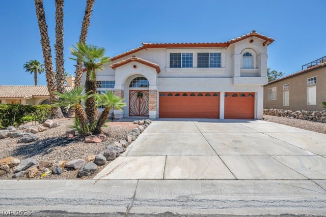 2553 Hummingbird Hill Avenue, Henderson, NV 89074 Mediterranean-inspired facade with terracotta roof tiles and a spacious concrete driveway welcomes you home.