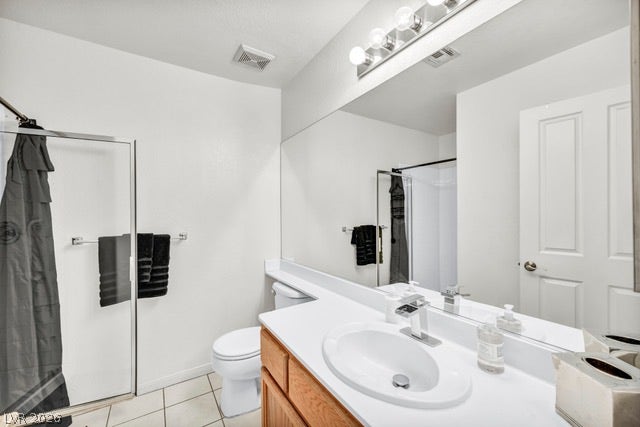 2553 Hummingbird Hill Avenue, Henderson, NV 89074 Well-lit primary bath features a shower with glass doors, a single vanity with abundant counter space, and a large mirror.