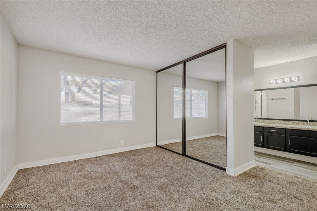 2343 Valleywood Road, Henderson, NV 89014 Ample natural light illuminates this bedroom, offering mirrored closet doors and a vanity.