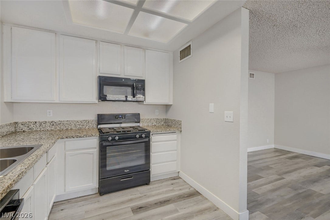 2343 Valleywood Road, Henderson, NV 89014 A compact kitchen presents white cabinetry, granite counters, and modern appliances.
