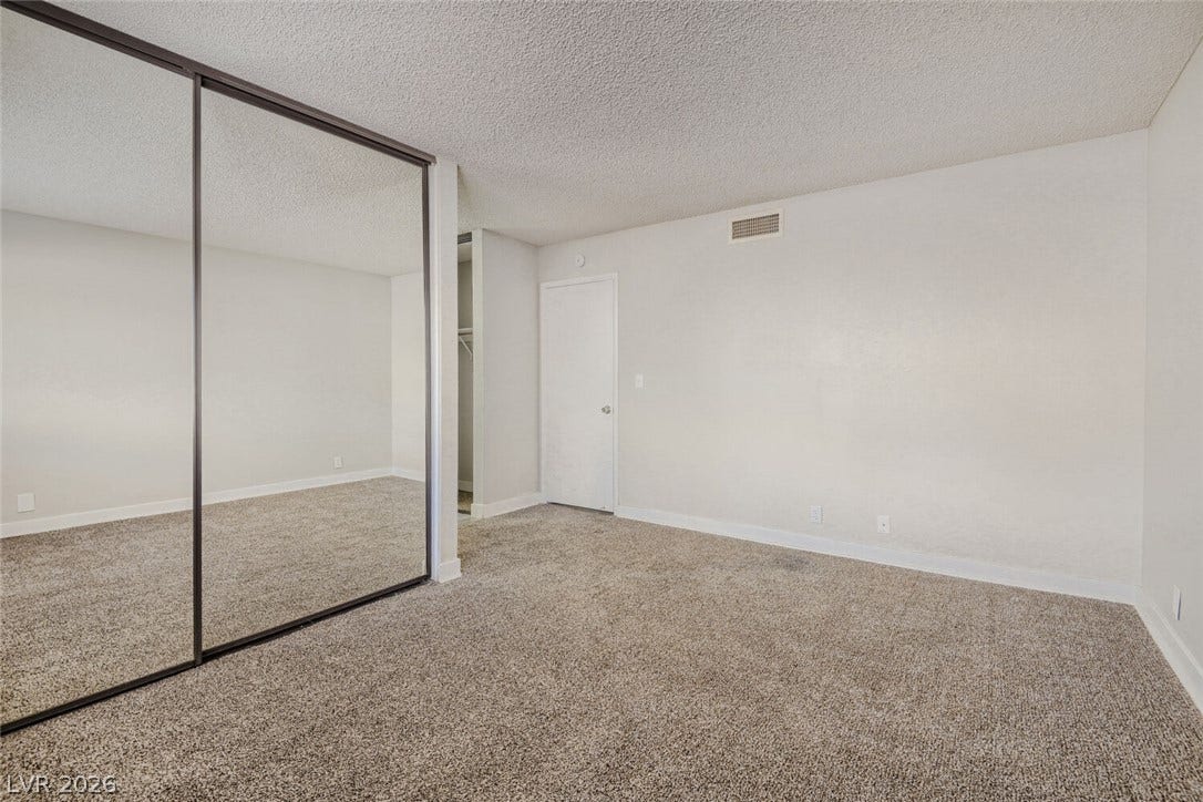 2343 Valleywood Road, Henderson, NV 89014 A spacious bedroom features plush carpeting and mirrored closet doors, creating an open and airy feel.